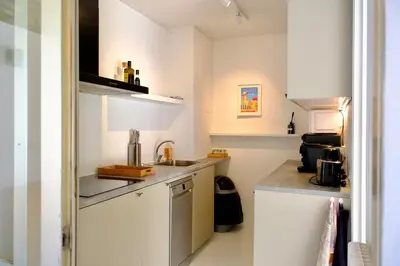 a small kitchen with white cabinets and a sink at Appartement de standing - quartier Martinez - 70m2 in Cannes