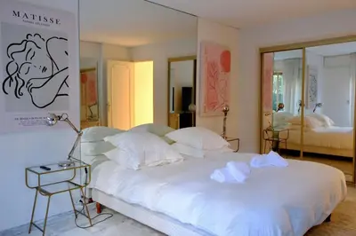 a bedroom with a large white bed with a side table at Appartement de standing - quartier Martinez - 70m2 in Cannes