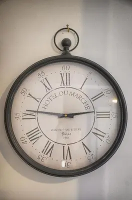 a clock with roman numerals is hanging on a wall at FRGK 