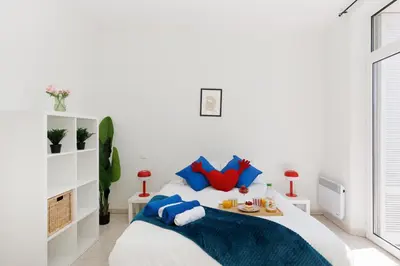 a white bedroom with a bed with blue pillows at BnGo l Ruby Suite l 2ch, 7p, vue mer, centre in Cannes