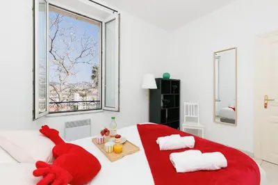 a living room with a red couch and a window at BnGo l Amber Suite l 2ch, 6 personnes, centre in Cannes