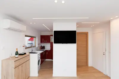 a white kitchen with a tv on a wall at Santa Cruz YourHostHelper in Cannes