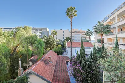 a house with a red roof with palm trees and buildings at Santa Cruz YourHostHelper in Cannes