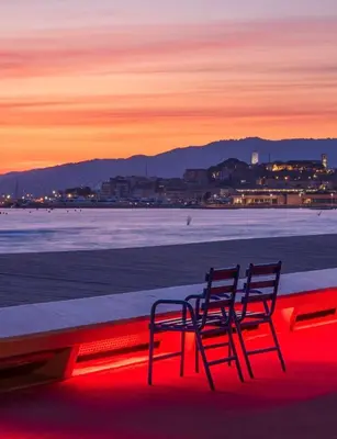 two chairs sitting on a ledge near the ocean at sunset at Appartement cosy proche de la Croisette in Cannes