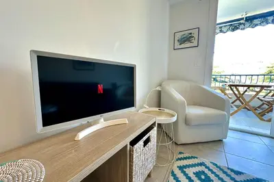 a living room with a flat screen tv and a chair at Cozy apartment with terrace in Cannes in Cannes