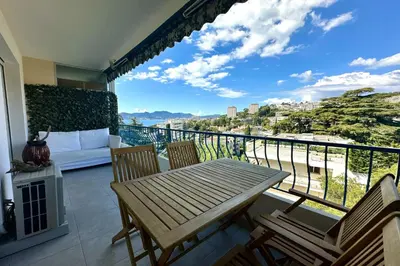 a balcony with a wooden table and chairs and a couch at Cozy apartment with terrace in Cannes in Cannes