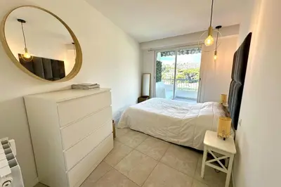a bedroom with a white bed and a mirror at Cozy apartment with terrace in Cannes in Cannes