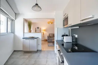 a kitchen with white cabinets and a black counter top at 2 pièces - Centre-ville Cannes - Grand lit double in Cannes