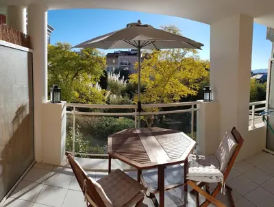 a table and chairs on a balcony with an umbrella at Chez Marie et Baptiste, bel appartement en résidence avec piscine, tennis in Le Cannet