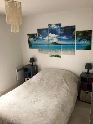 a bedroom with four paintings on the wall at Chez Marie et Baptiste, bel appartement en résidence avec piscine, tennis in Le Cannet