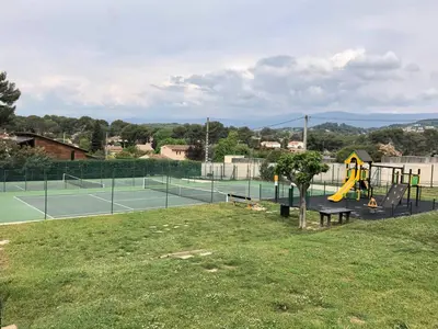 a playground with two tennis courts and a tree at Chez Marie et Baptiste, bel appartement en résidence avec piscine, tennis in Le Cannet
