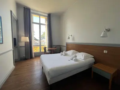 a bedroom with two beds and a large window at Hôtel-résidence-Windsor in Cannes