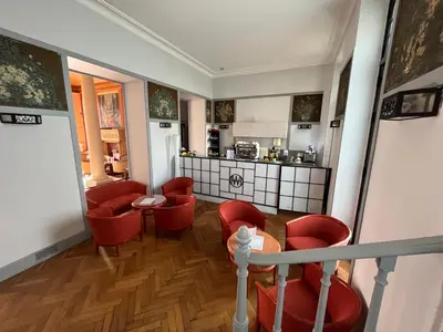 a living room with red chairs and a kitchen at Hôtel-résidence-Windsor in Cannes