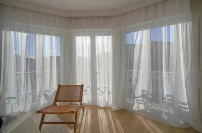 a chair sitting in front of a large window at Mimosa 2BR with Balcony - Walk to Palais and Beach in Cannes