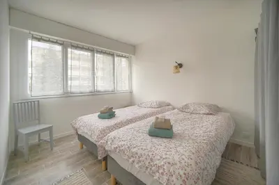 a bedroom with two beds and a chair and windows at Calme 2 Chambres BALCON VUE JARDIN-CARNOT A2B266 in Cannes