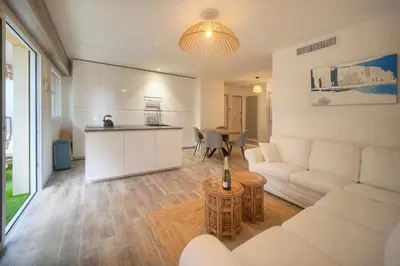 a living room with a white couch and a kitchen at Calme 2 Chambres BALCON VUE JARDIN-CARNOT A2B266 in Cannes