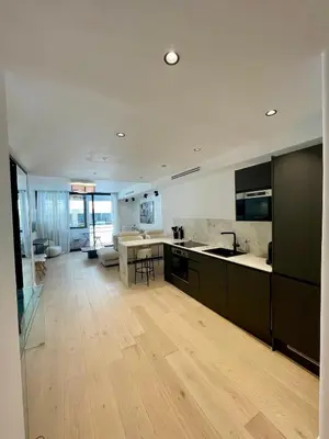 a kitchen with wooden floors and a large room with a table at T2 chic et moderne à deux pas de la Croisette in Cannes