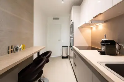 a kitchen with a counter and two black chairs at Résidence 3p Traversant à 2 Min Des Plages, Parking Privé - 3P traversant à 2 min des plages, parking privé MAE-1583 in Cannes