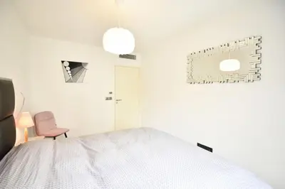 a bedroom with a white bed and a pink chair at Résidence 3p Avec Terrasse Et Piscine Au Coeur Du Palm Beach - 3P avec terrasse et piscine au coeur du Palm Beach MAE-1593 in Cannes
