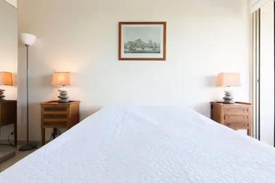 a white bedroom with a large white bed with two lamps at Résidence Vue Mer, Cannes Croisette, Au Pied Des Plages - Vue Mer, Cannes Croisette, au Pied des Plages MAE-1653 in Cannes