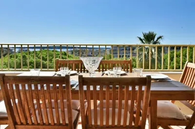 a wooden table with chairs and wine glasses on a patio at Résidence 3p Proche Centre Ville, Piscine Et Vue Mer - 3P proche centre ville, piscine et vue mer MAE-1673 in Cannes