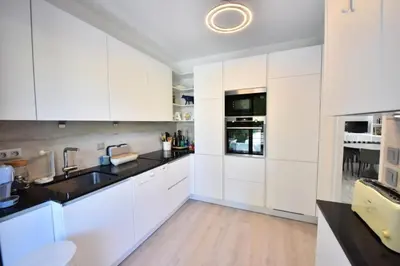 a white kitchen with black countertops and white cabinets at Résidence 4p Avec Grande Terrasse Et Piscine - 4P avec grande terrasse et piscine MAE-1693 in Cannes