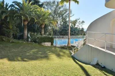 a yard with palm trees and a swimming pool at Résidence 2p Avec Terrasse, Vue Mer, Piscine Et Parking - 2P avec terrasse, vue mer, piscine et parking MAE-1723 in Cannes