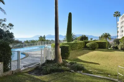 a fence with a palm tree and a pool at Résidence 2p Avec Terrasse, Vue Mer, Piscine Et Parking - 2P avec terrasse, vue mer, piscine et parking MAE-1723 in Cannes