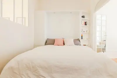 a white bedroom with a large bed with pink pillows at Résidence Hyper Centre Cannes - 4p à 100m Du Palais - Hyper centre Cannes - 4P à 100m du palais MAE-1873 in Cannes