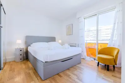 a white bedroom with a bed and a yellow chair at Résidence 2p De Style Avec Terrasse, Plages Et Commerces à Pied - 2P de style avec terrasse, plages et commerces à pied MAE-1913 in Cannes
