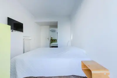 a bedroom with a white bed and a wooden bench at Résidence 90m2 Sur La Croisette Avec Terrasse & Vue Mer - 90m2 sur la Croisette avec terrasse & vue mer MAE-1963 in Cannes