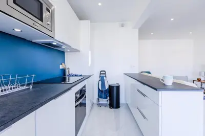 a kitchen with white cabinets and a blue accent wall at Résidence 2 Pièces Cozy à 5 Minutes à Pied De La Croisette - 2 pièces cozy à 5 minutes à pied de la Croisette MAE-1983 in Cannes