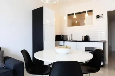 a kitchen with a white table and black chairs at Résidence 3p Moderne Et Cosy Aux Pieds De La Croisette ! - 3P moderne et cosy aux pieds de la Croisette ! MAE-2003 in Cannes