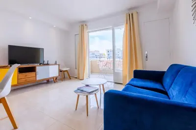 a living room with a blue couch and a tv at Résidence 3p De Style Avec Balcon à 3 Min De La Croisette - 3P de style avec balcon à 3 min de la Croisette MAE-2013 in Cannes