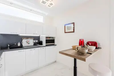 a kitchen with white cabinets and a wooden table at Résidence 2p De Style Avec Terrasse, Domaine Privé Palm Beach - 2P de style avec terrasse, domaine privé Palm Beach MAE-2053 in Cannes