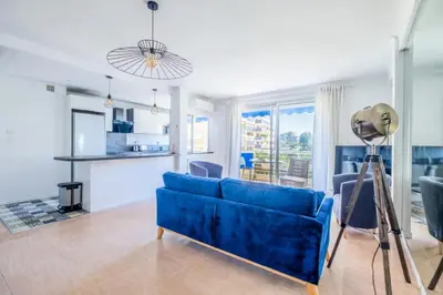 a living room with a blue couch and a kitchen at Résidence 3p à 100m Des Plages, Terrasse Et Parking - 3P à 100m des plages, terrasse et parking MAE-2073 in Cannes