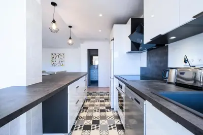 a kitchen with white cabinets and a black counter top at Résidence 3p à 100m Des Plages, Terrasse Et Parking - 3P à 100m des plages, terrasse et parking MAE-2073 in Cannes