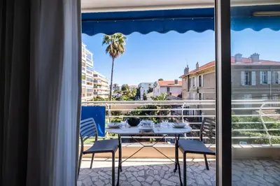 a table and chairs on a balcony with a view of a palm tree at Résidence 3p à 100m Des Plages, Terrasse Et Parking - 3P à 100m des plages, terrasse et parking MAE-2073 in Cannes