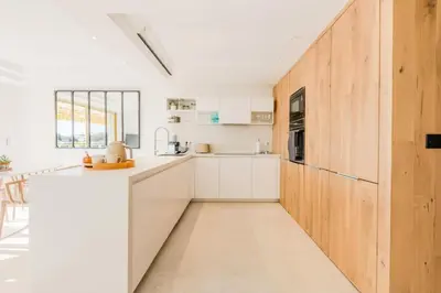 a kitchen with white cabinets and a wooden wall at Résidence 4p De 96m² Sur Les Hauteurs De Cannes - 4P de 96m² sur les hauteurs de Cannes MAE-2083 in Cannes