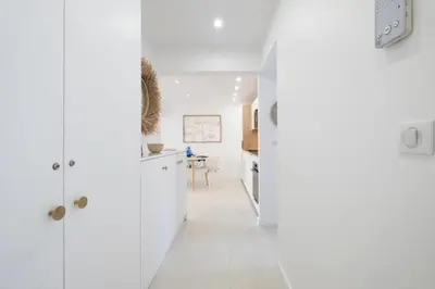 a white kitchen with white cabinets and a table at Résidence 3p De Style à Deux Pas De La Croisette & Commerces - 3P de style à deux pas de la Croisette & commerces MAE-2103 in Cannes