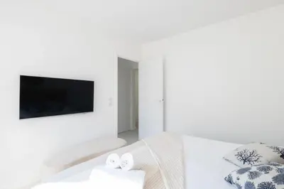 a white bedroom with a tv and towels on a bed at Résidence 3p De Style à Deux Pas De La Croisette & Commerces - 3P de style à deux pas de la Croisette & commerces MAE-2103 in Cannes