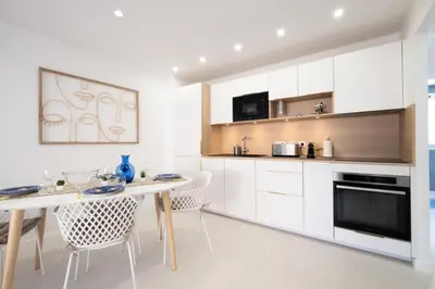 a kitchen with white cabinets and a table and chairs at Résidence 3p De Style à Deux Pas De La Croisette & Commerces - 3P de style à deux pas de la Croisette & commerces MAE-2103 in Cannes