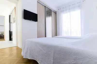 a white bedroom with a bed and a flat screen tv at Résidence 4p Vue Mer Exceptionnelle, Aux Pieds Des Plages - 4P vue mer exceptionnelle, aux pieds des plages MAE-2113 in Cannes