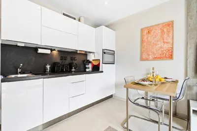 a kitchen with white cabinets and a wooden table at Résidence Centre Ville De Cannes, 2p Moderne Avec Terrasse - Centre ville de Cannes, 2P moderne avec terrasse MAE-2133 in Cannes