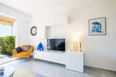 a living room with a tv and a yellow chair at Résidence Rare ! Superbe 3 Pièces Avec Jardin Face à La Mer - RARE ! Superbe 3 pièces avec jardin face à la mer MAE-2143 in Cannes