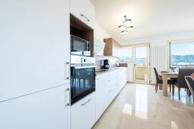 a kitchen with white cabinets and a dining room at Résidence 4p Proche Hyper Centre, Vue Mer, Parking - 4P proche hyper centre, vue mer, parking MAE-2153 in Cannes