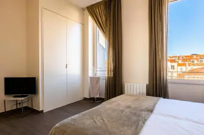 a bedroom with a bed and a tv and a window at Résidence 3 Pièces Rue D’antibes à Deux Pas Du Palais Des Festivals - 3 pièces rue d’Antibes à deux pas du Palais des festivals MAE-2263 in Cannes