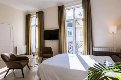 a bedroom with a bed and two chairs and a tv at Résidence 3 Pièces Rue D’antibes à Deux Pas Du Palais Des Festivals - 3 pièces rue d’Antibes à deux pas du Palais des festivals MAE-2263 in Cannes