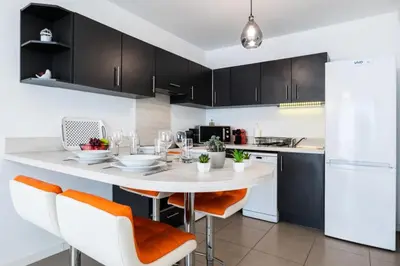 a kitchen with a white table with orange chairs at Résidence 2p Avec Piscine Au Palm Beach - 2P avec piscine au Palm Beach MAE-2313 in Cannes