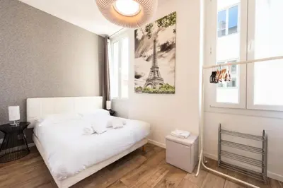a bedroom with a white bed and a picture of the eiffel tower at Résidence Hyper Centre, Croisette, Plages Et Palais à Pied - Hyper centre, Croisette, plages et Palais à pied MAE-2333 in Cannes